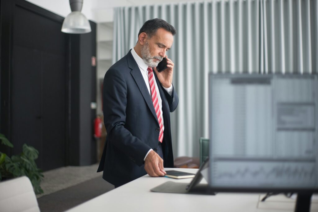 pexels-photo-8353782-8353782 Professional man in a business suit on a phone call in a modern office setting.
